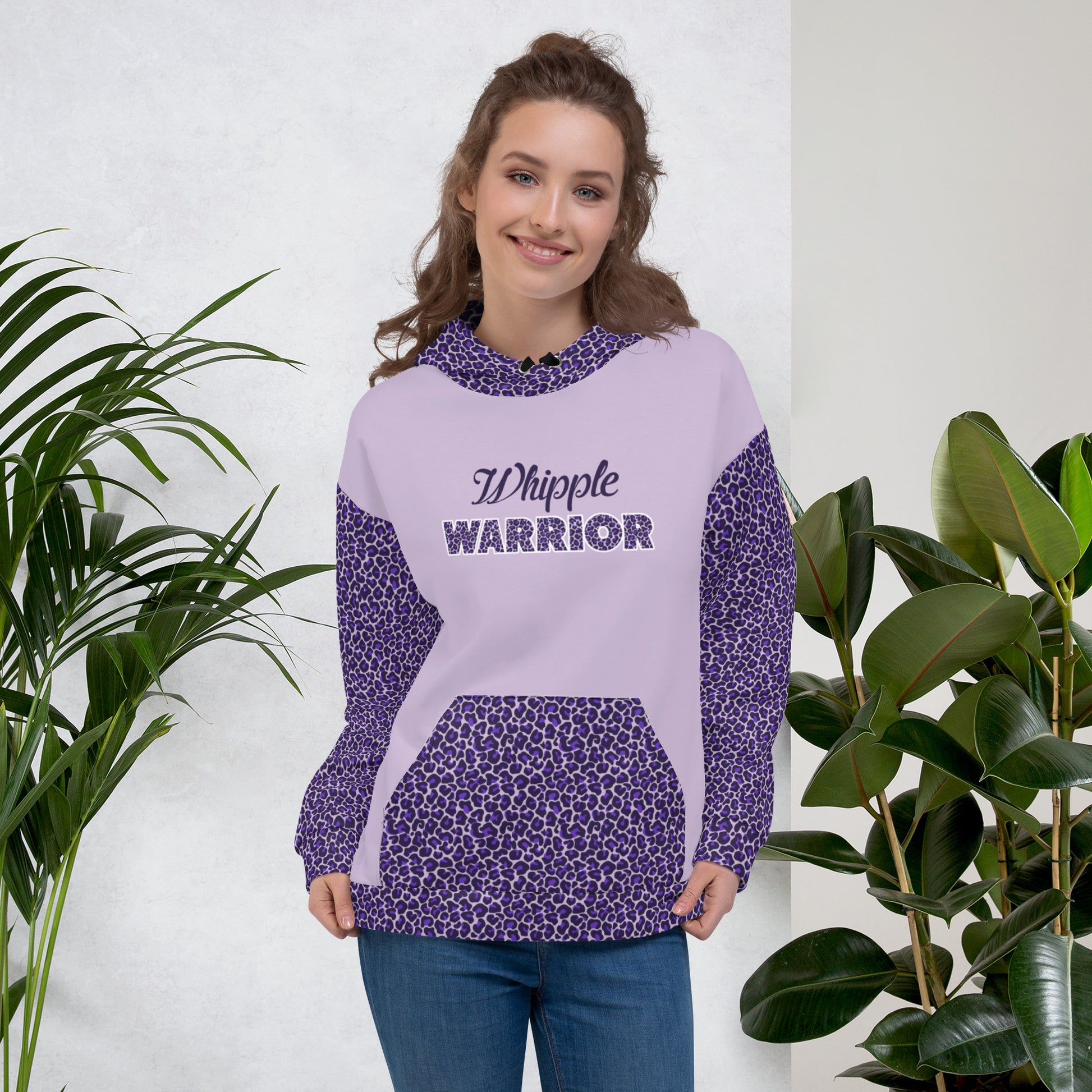 A woman modeling my purple Whipple Warrior hooded sweatshirt. I created the hoodie design with purple leopard spots on both sleeves, the hood, the pocket, and the bottom fold. The front of the design reads "Whipple WARRIOR" and the back has a purple ribbon printed on it. I created the design to raise awareness for pancreatic cancer, pancreas disease,  and going through the Whipple Surgery.