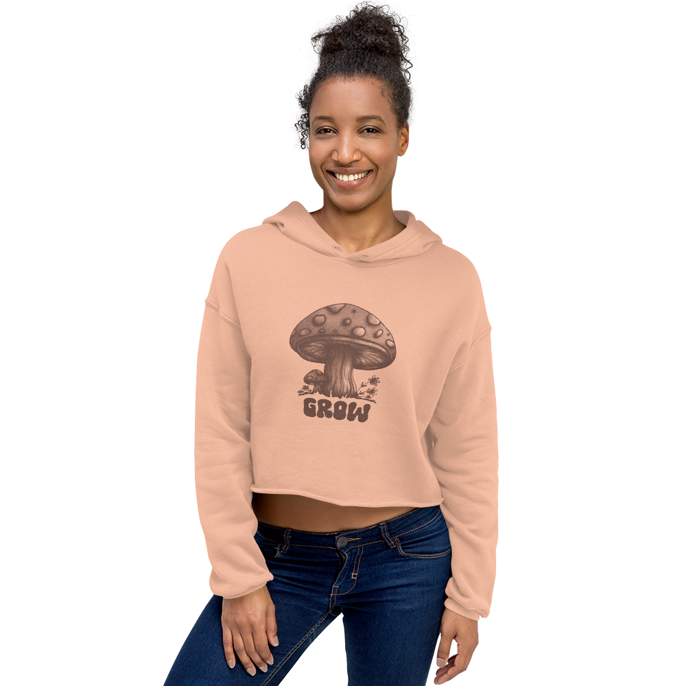 A model wearing my hand drawn design of cute mushrooms accented with the word "GROW". This is a peach cropped hoodie for women with brown print. There are beautiful line and cross-hatched details, giving the hoodie a sketched, natural look.